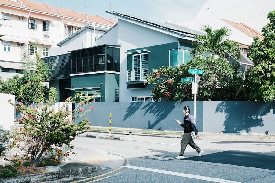 Person crossing the street in front of a modern house